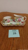 Porcelain cream and sugar set with tray showing floral design and gold trim.
