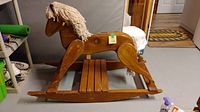Side view of the wooden rocking horse showing yarn mane and wear on wood surface
