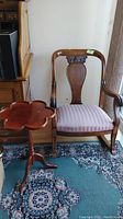 Wooden rocking chair and side table shown together to display entire lot.