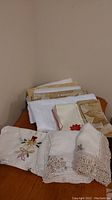 Photo showing folded Christmas and decorative white linens including table runner and tablecloths stacked on a wooden surface