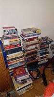 Photo showing multiple stacks of various books on the floor and against the wall.