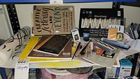 Full display of calligraphy pens, nibs, ink bottle, instructional books, and pads of paper arranged on a table.