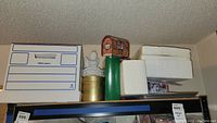 Top shelf with several boxes including a green Rudolph decorative item and white boxes