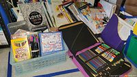 Wide view showing various coloring books and supplies including colored pencils and markers stored in baskets and pencil cases