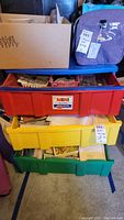Full view of red, yellow, and green plastic drawers stacked with various containers and craft supplies inside each drawer
