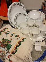 Corelle dishware and holiday hand towels, showing all dishes and towels arranged for display in storage area.