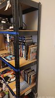 Side view of metal shelving unit filled with books and a small television.