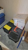 Photo of two black and orange tool boxes and one cardboard box with label for velcro and elastic tape