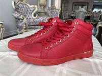 Side view of both red Aldo high-top sneakers on a white cloth, showing the gold accents on the sole and the stitched design.