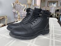 Side view of the black winter boots showing leather texture, laces, and overall condition.