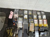 Overview photo showing multiple iPhone cases, camera lenses, Apple Watch stand, screen protectors arranged on a counter