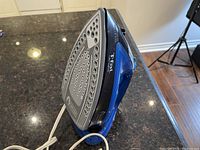 Photo showing side and soleplate of T-fal Ultraglide iron, blue and black with steam holes.