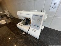 Side angle showing front and left side of Kenmore 22 sewing machine with power cable and foot switch placed on top.