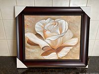 Front view of the framed painting of a rose in beige and brown tones with protective corner covers