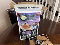 Open box of Northern Eskimo propane heater/cooker with product image and information in French and English.