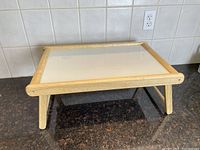 Side view of the serving tray with legs folded out, showing the wooden frame and white top surface.