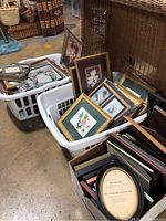 Photo showing baskets and boxes filled with various picture frames and botanical wall art, capturing the full lot.