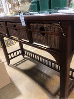 Side view of wooden buffet showing four wicker basket drawers and bottom slatted support stretcher.