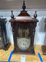 Front view of the wooden Polaris wall clock showing the glass front and clock face with Roman numerals.