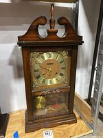 Front angled view showing the wooden Wangja clock with Roman numerals and pendulum.
