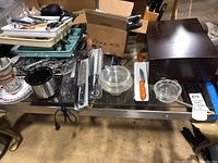 Overall view of all items on stainless steel table: flatware chest, knives, bowls, canister, cutting board and organizer tray