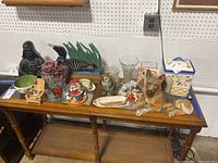 Overview of all items on wooden table showing various figurines, vases, cookie jar, candles, and bowls