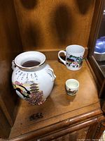 Porcelain covered dish with lid featuring traditional Japanese artwork, mug with Japanese figure, and small cup or bell with figure