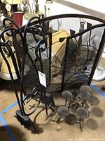 Front view showing rust-colored fireplace screen with leaf design, curling metal tools stand, and multiple round candlestick holders.