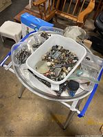 Photo showing assortment of various hardware parts in bins on top of metal table with blue supports