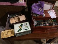 Overview of four jewelry boxes including one with broken lid and assorted souvenir keychains with purple pouch on table.