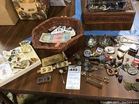 Overview of collection including pocket watch, pins, tie tacks, Indian currency, stamps, and keychains displayed on a table.