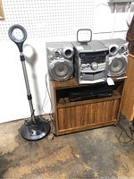 Photo of the full lot showing JVC stereo system with speakers, Harman Kardon disc player below it, and Memorex microphone stand to the left.