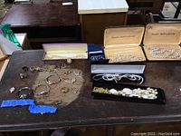 Overview of all jewelry pieces on a table including rings, watches, and pearl necklaces in boxes