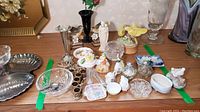 Overview of collection showing varied porcelain figurines, small dishes, candle holders, and souvenir spoons
