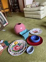 Overview of the collection showing pink spherical vase, blue square vase, blue round bowl, red plate, blue and white ornamental bowl, Botanical Garden floral ceramic plate