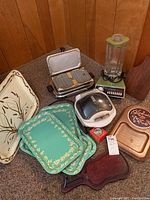 Image showing kitchen appliances including a Waring Fiesta 300 blender, George Foreman grill, vintage wooden waffle maker, decorative trays, and wooden boards.