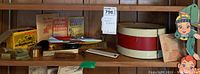 Photo of multiple shelves with Brownie Holiday camera box, tin drum, retail store stamps, slide measure, and Howdy Doody puppets hanging nearby.