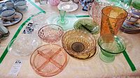 Wide view of mid-century colored glass bowls and Waterford crystal items on a table with a yellow tablecloth