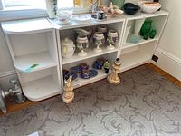Photo of multiple painted wood shelf units with some decorative items on them showing the style and condition