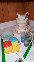 Stacked Taylor Smith & Taylor Ever Yours dinnerware with blue floral pattern including plates, bowls, and a pitcher, alongside Franciscan dishes.