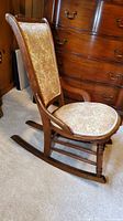 Side view of rocking chair showing curved wooden frame, rockers, and floral tapestry seat and backrest.