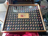 Full view of the framed pin collection showing many colorful country flag pins arranged in rows over a black background.
