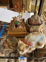 Photo showing the ceramic jar with lid, ceramic cat figurine, beaded wire floral/bird ornament, and small glass vase on shelf