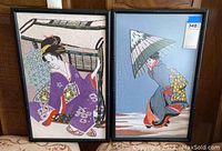 Photo showing two embroidered Asian style wall art pieces in black bamboo-like frames featuring traditional Japanese figures.