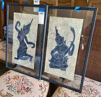 Two framed Asian style papyrus prints displayed side-by-side showing traditional figures