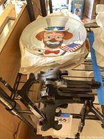 Photo showing round ceramic plate featuring detailed clown with Uncle Sam hat and American flag, placed on plate stands.