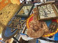 Photo of Judaica decorative items arranged including framed art, wooden Star of David, carved wood artworks and decorative plates.