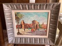 Framed oil painting showing a historic stone structure with people walking, signed by the artist.