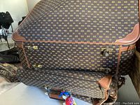 Photo of large vintage luggage case showing dark brown monogram fabric and brown leather corners with brass locks.