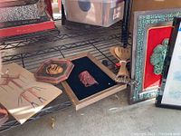 Shelf with wood carving mask, framed wood carved face, wooden salad tongs, stone art frame and small octagonal carved face piece.
